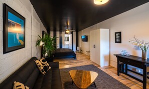 Una sala moderna con un sofá negro, una mesa de centro de madera y una planta grande.