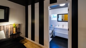 Et moderne badeværelse med hvid vask, spejl og toilet.
