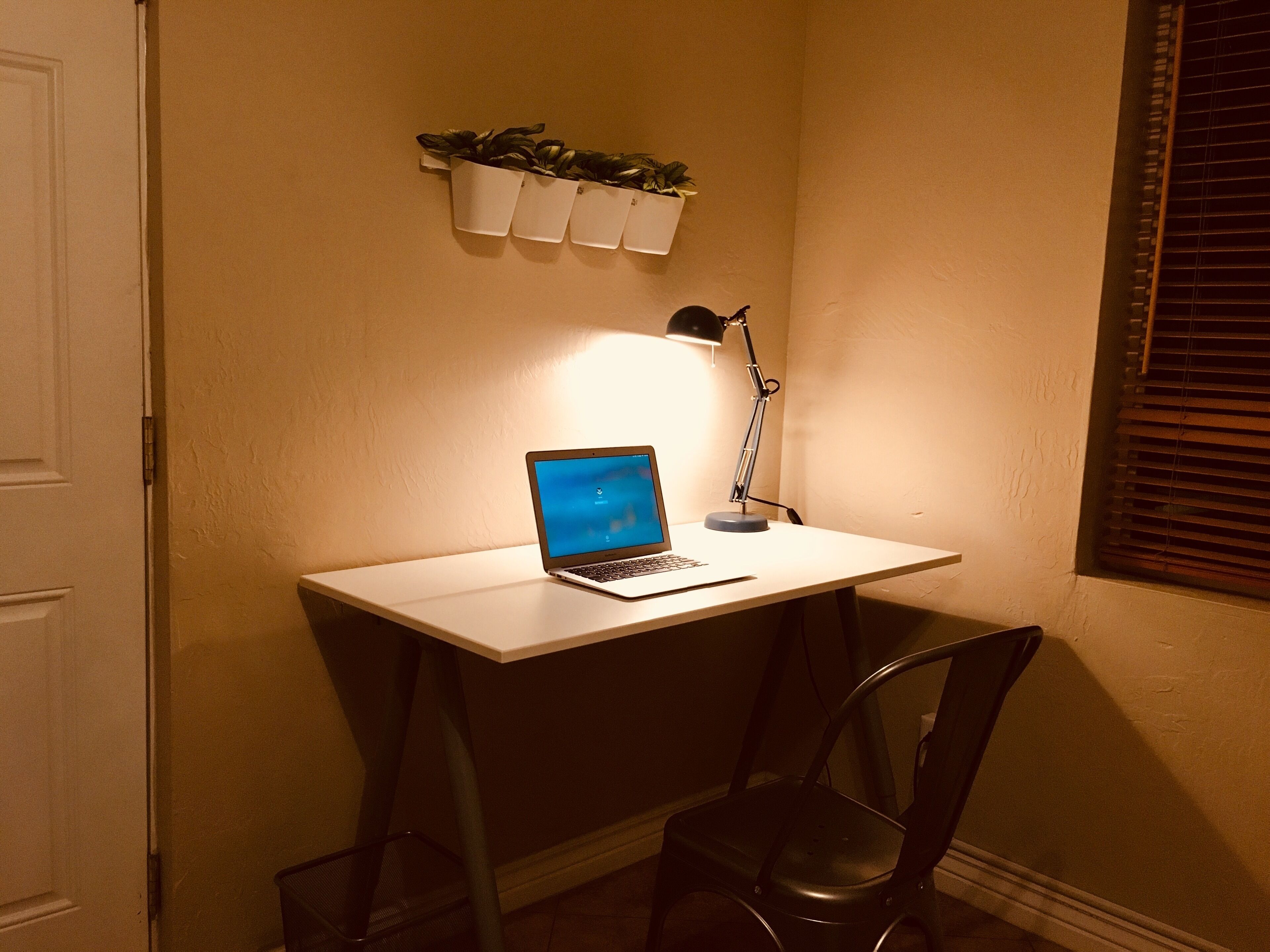 A corner desk with a laptop, a desk lamp, and a chair.
