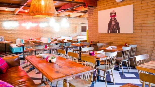 Un restaurant aux murs de briques, aux tables et aux chaises en bois.