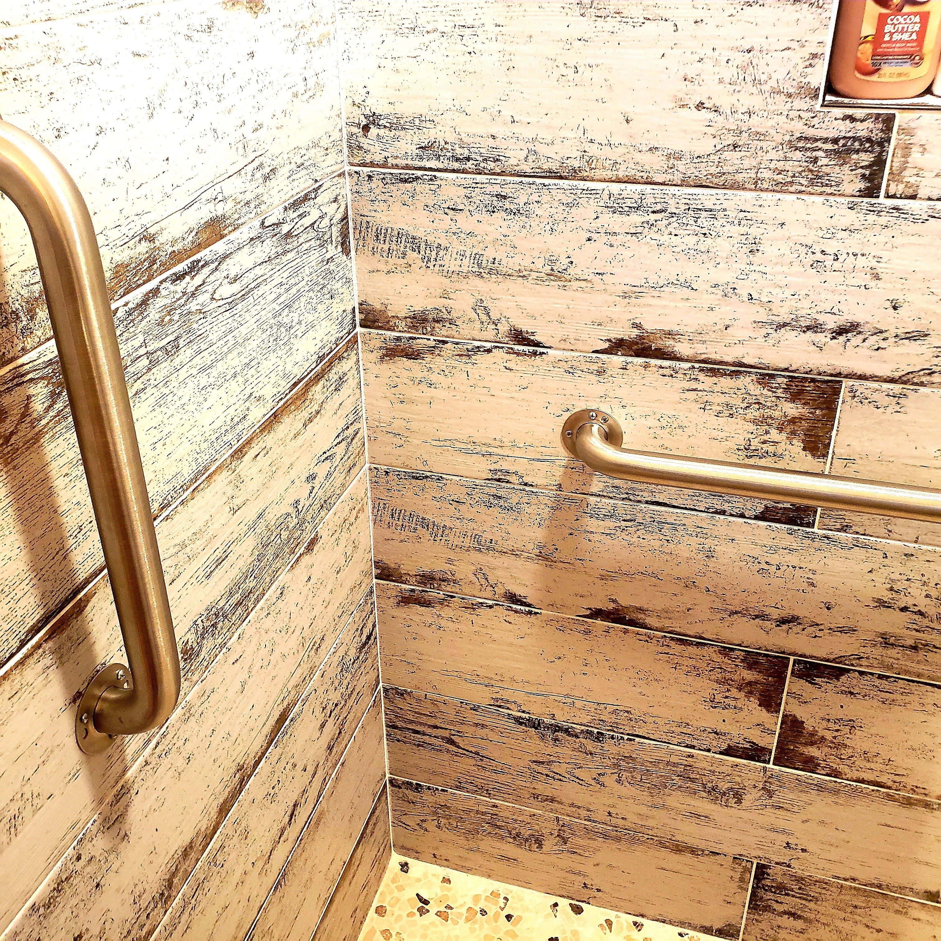 A bathroom with a handrail and a tiled wall.