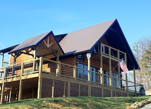 Eine zweistöckige Blockhütte mit Balkon, großen Fenstern und einer amerikanischen Flagge.