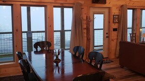 Un interior de madera con una mesa de comedor, sillas y una araña.