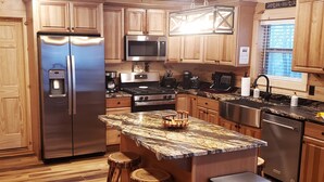 Una cocina moderna con gabinetes de madera, electrodomésticos de acero inoxidable, encimera de granito y una isla integrada con taburetes.
