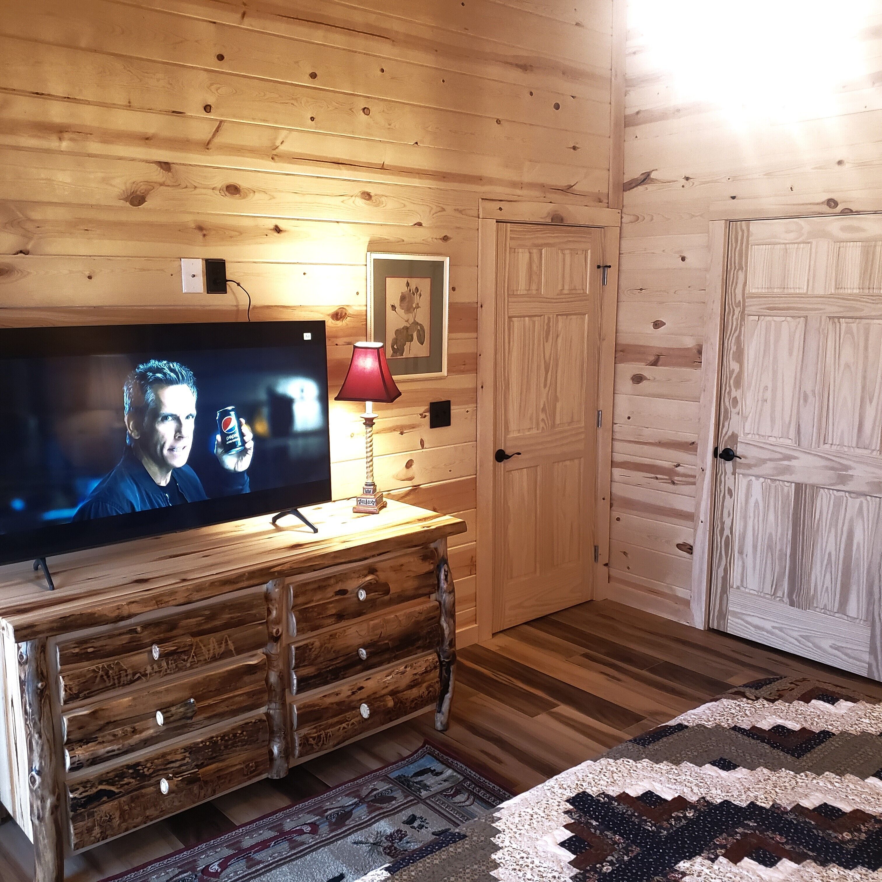 Ein Zimmer mit Holzvertäfelung, einem Fernseher auf einer Holzkommode, einer roten Lampe und einer Tür.