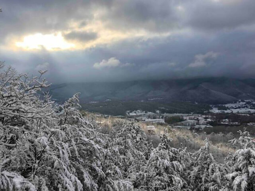 Schneebedeckte Landschaft mit Blick auf eine Stadt und Berge im Hintergrund.