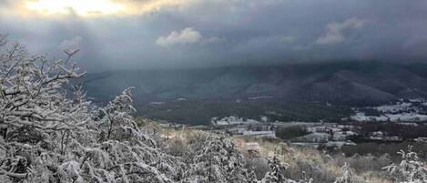 Schneebedeckte Landschaft mit Blick auf eine Stadt und Berge im Hintergrund.