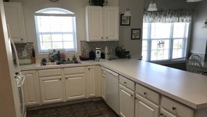 A kitchen with white cabinets, a sink, and a window. - Charming 3 Bedroom Condo in Myrtlewood (Myrtle Beach)