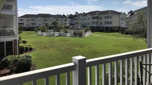 A residential complex with multiple two-story buildings, a central lawn, and a white fence. - Charming 3 Bedroom Condo in Myrtlewood (Myrtle Beach)