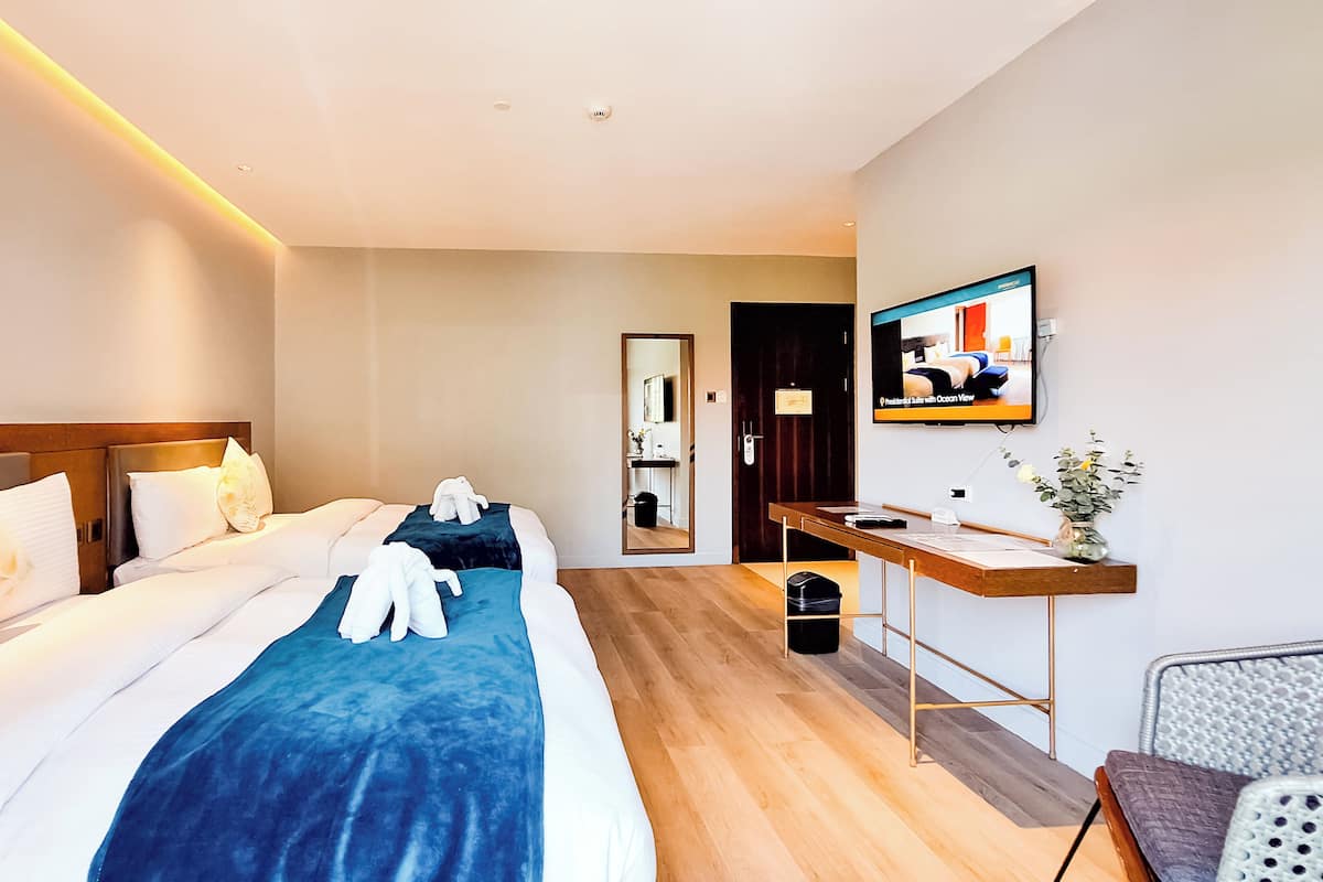Una camera d'albergo con un letto grande, una scrivania, una sedia, una televisione e uno specchio.