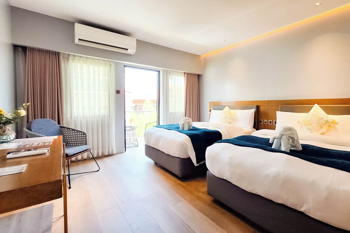 Una camera d'albergo con due letti, una scrivania e una sedia.