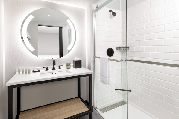 Een moderne badkamer met een wit wastafelmeubel, spiegel en een douchecabine van glas.