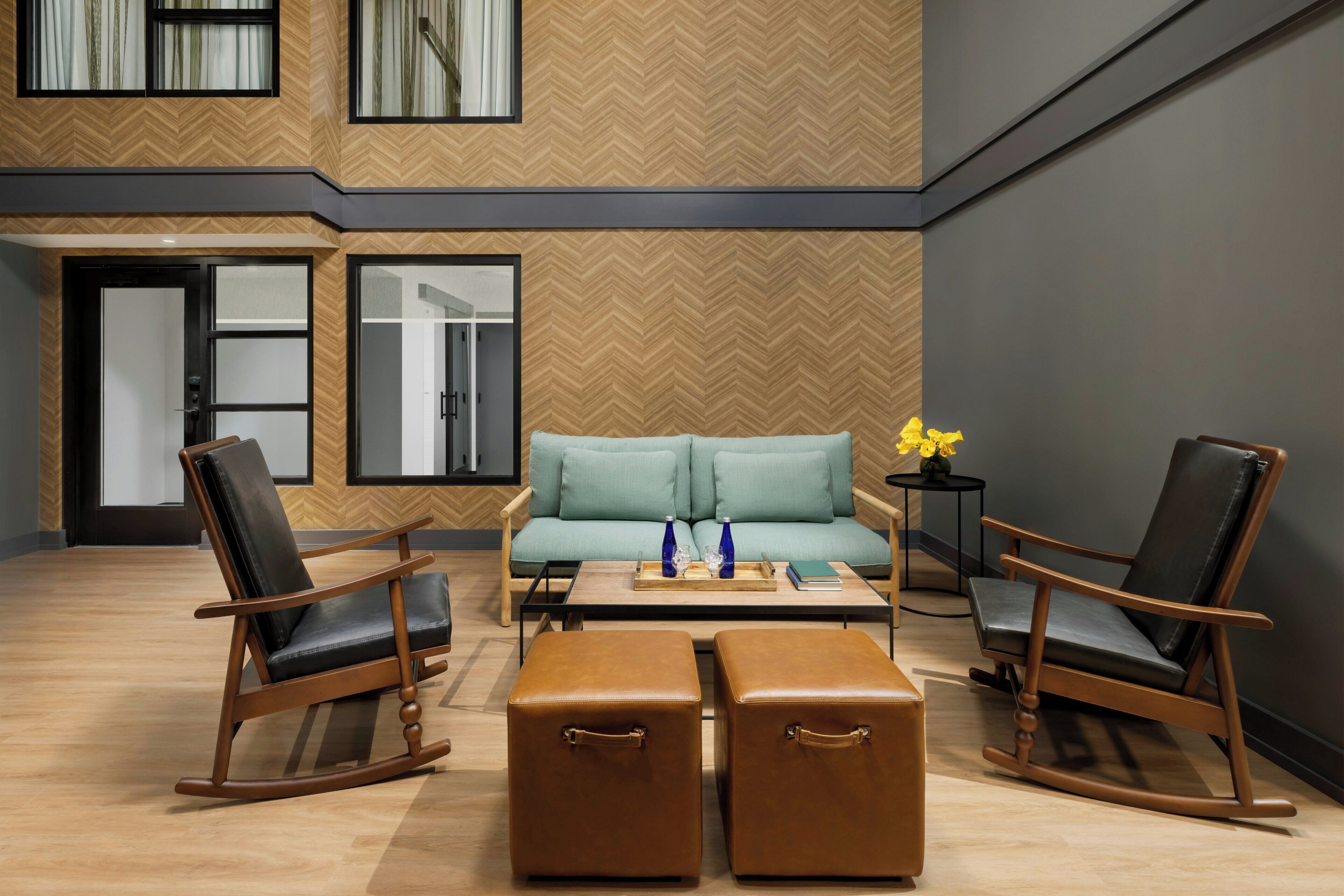 A modern living room with a sofa, two rocking chairs, a coffee table, and a small side table with a vase.