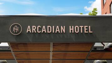 A sign for the Arcadian Hotel with a modern design and a logo.