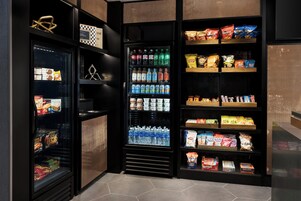 Zona de venta automática con diversas marcas de aperitivos, bebidas y café.