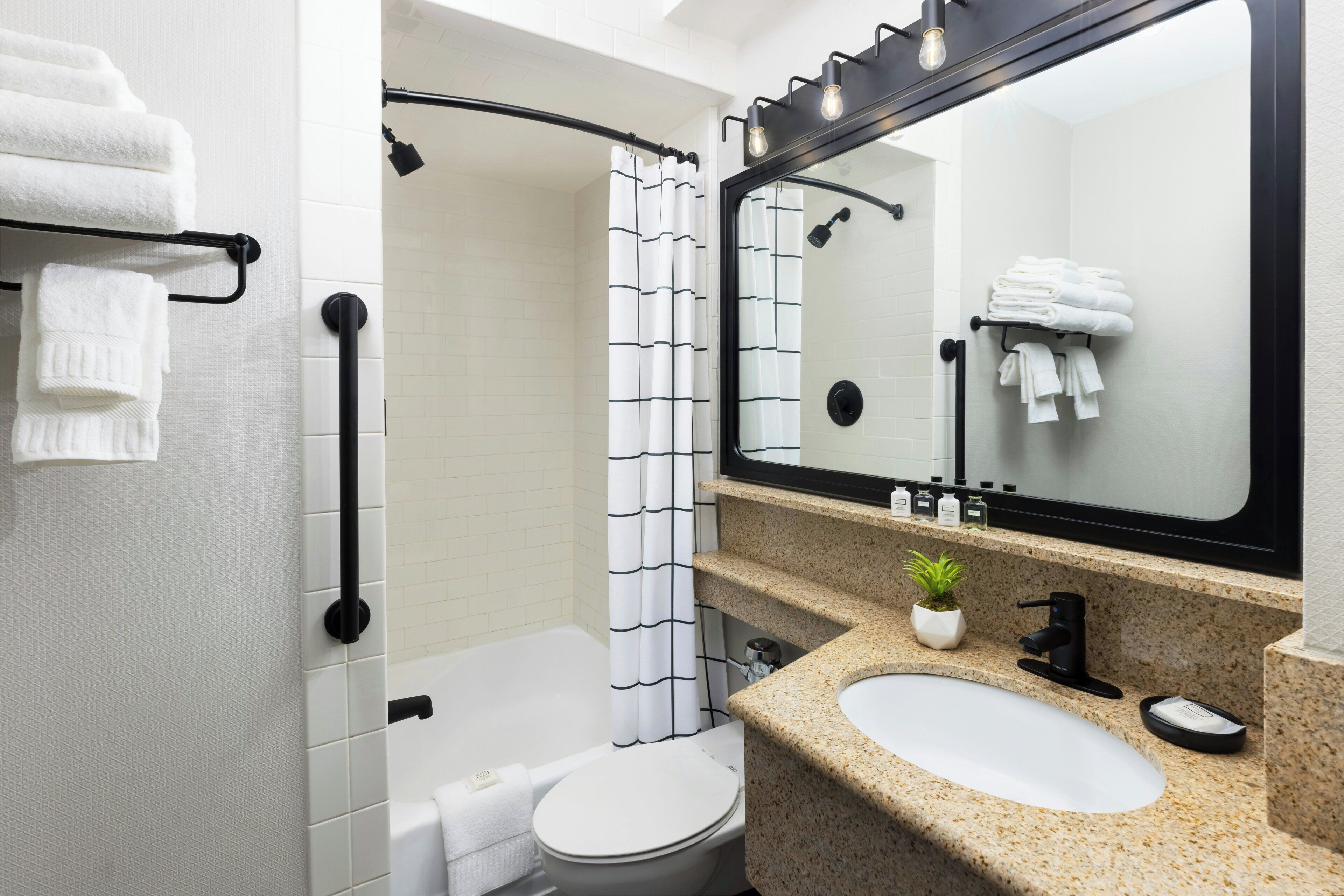Une salle de bain moderne équipée d’une douche, de toilettes, d’un lavabo et d’un grand miroir.