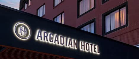 The exterior of the Arcadian Hotel with its illuminated signage.