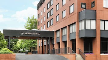 A hotel entrance with a covered canopy, a brick facade, and a staircase leading to the entrance.