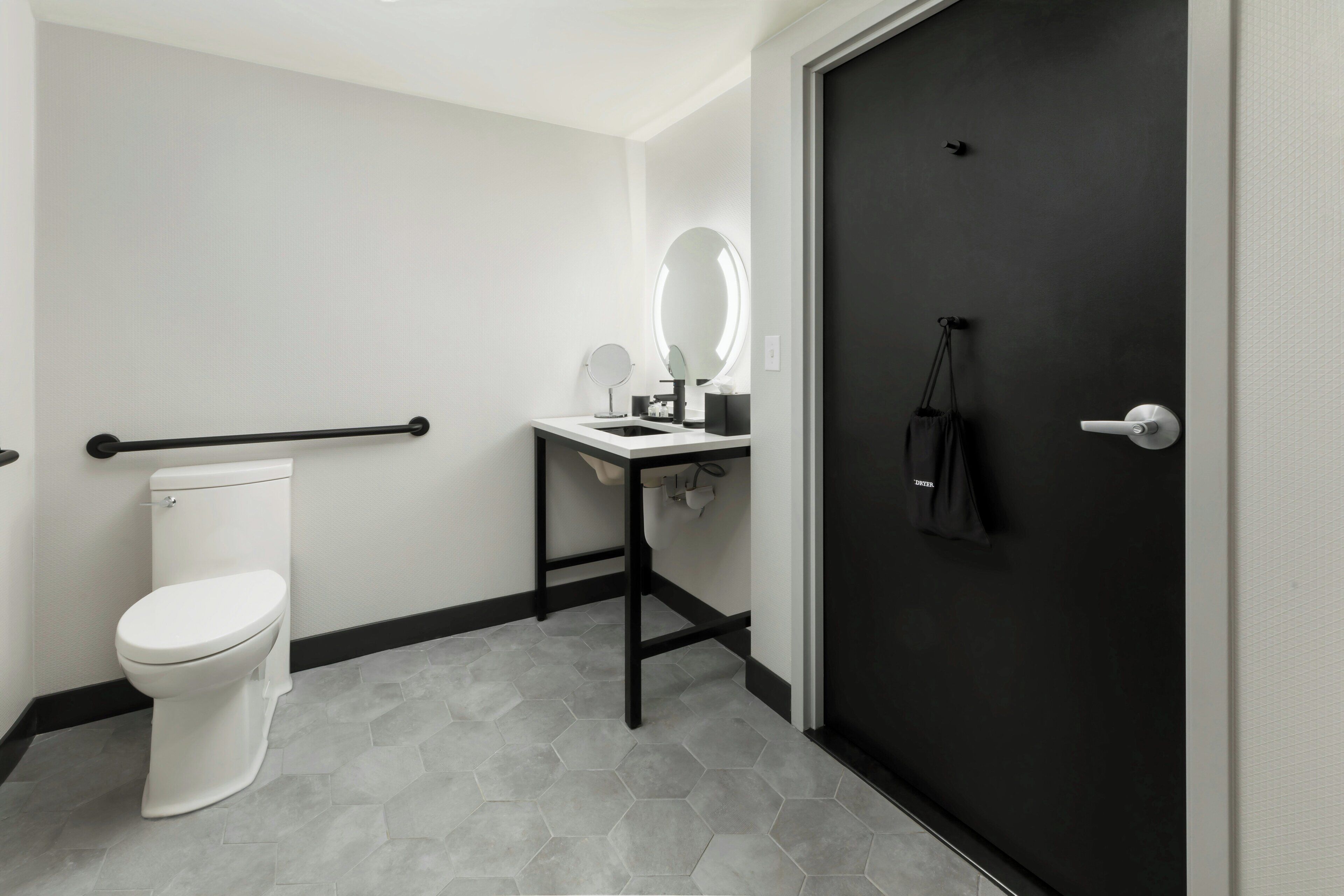 Un baño con inodoro, lavabo con espejo y puerta negra.