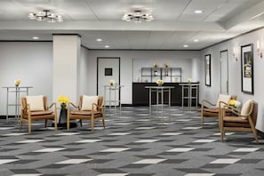 A hotel lobby with a check-in desk, seating area, and a patterned floor. - Arcadian Hotel (Brookline)