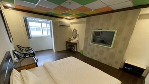 A hotel room with a bed, a desk with a chair, a window, and a TV mounted on the wall. - Yi Sian Hot Spring Hotel (Taimali)