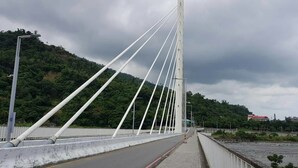 A cable-stayed bridge with a clear road and a sidewalk, surrounded by greenery and a cloudy sky. - Yi Sian Hot Spring Hotel (Taimali)