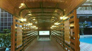 A corridor with wooden shelves on both sides, leading to a pool area. - Yi Sian Hot Spring Hotel (Taimali)