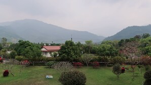 Zona residencial amb una casa, vegetació abundant i muntanyes al fons.