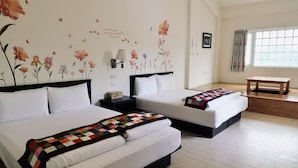 Habitació d'hotel amb dos llits, un sòl de fusta, una finestra amb cortines i una taula petita.