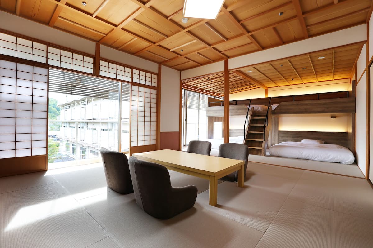 A traditional Japanese room with tatami flooring, a low wooden table, and a futon bed.