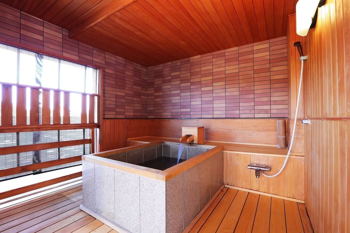 A wooden sauna with a stone hot tub, wooden benches, and a wooden ceiling.
