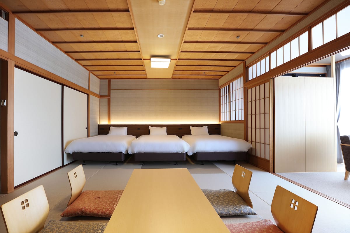 A traditional Japanese-style room with tatami flooring, a low ceiling with wooden beams, and a sliding door.