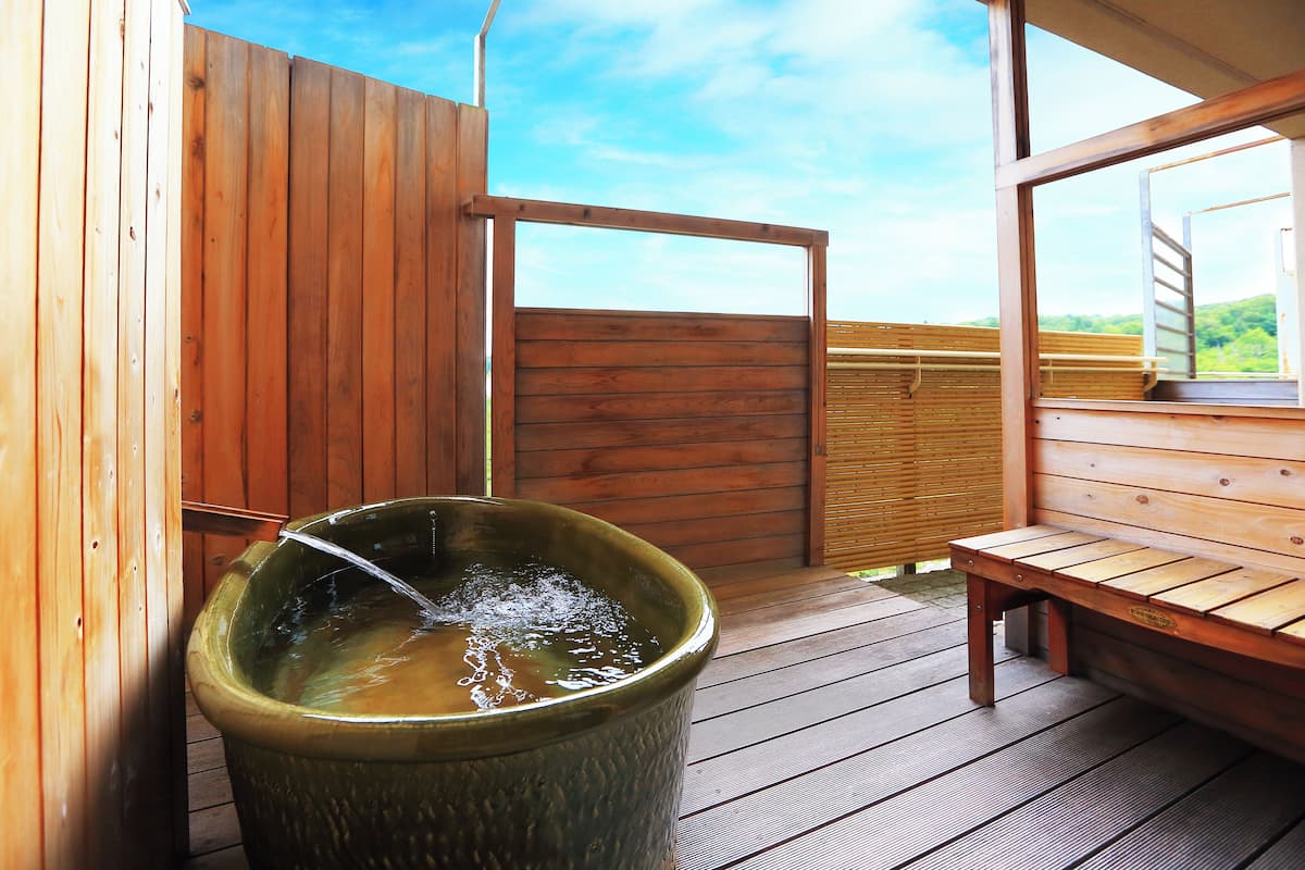 A wooden deck with a hot tub, wooden benches, and a wooden fence.
