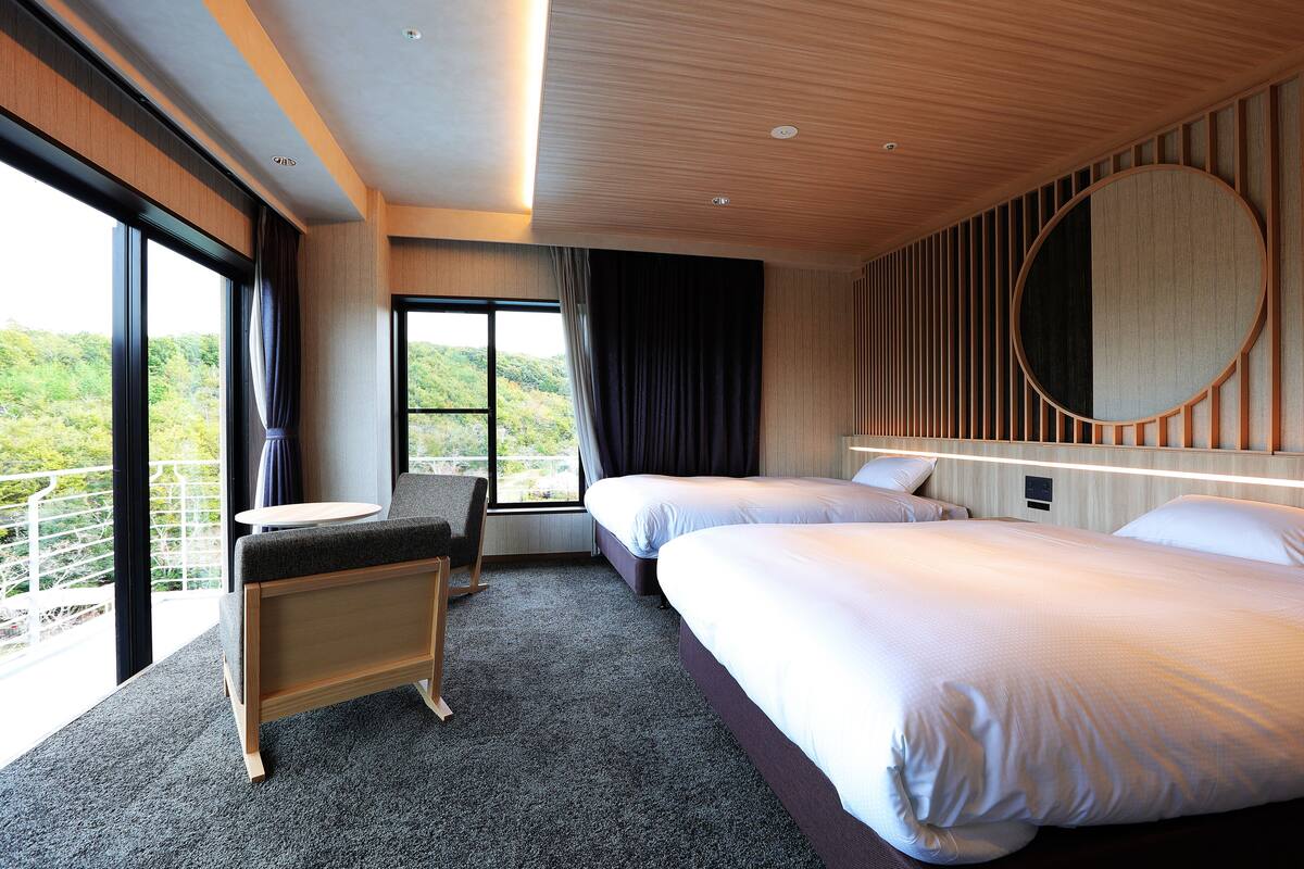 A hotel room with two beds, a small table, and a chair.