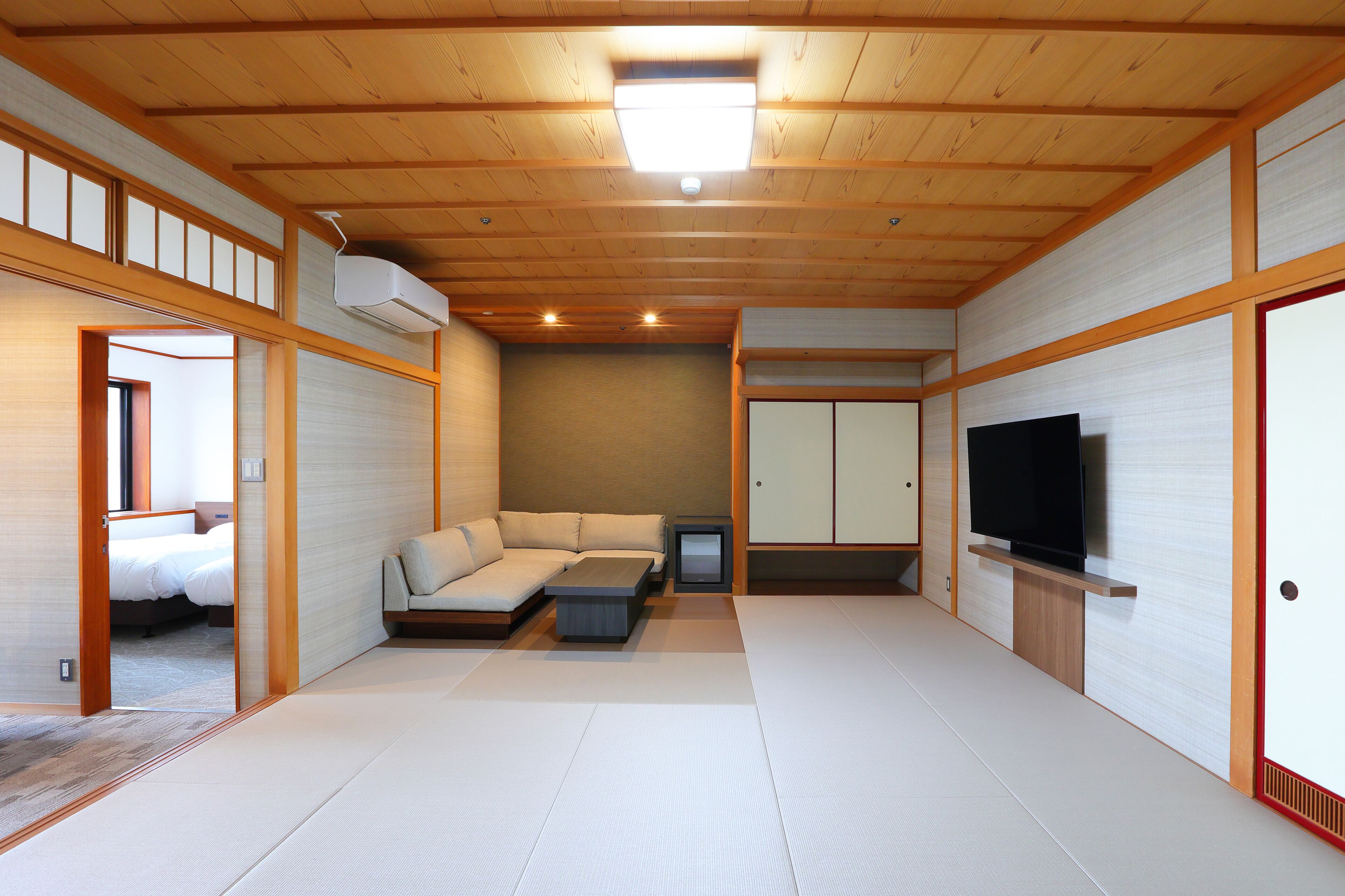 A modern interior with tatami flooring, a sofa, a TV, and a cabinet.