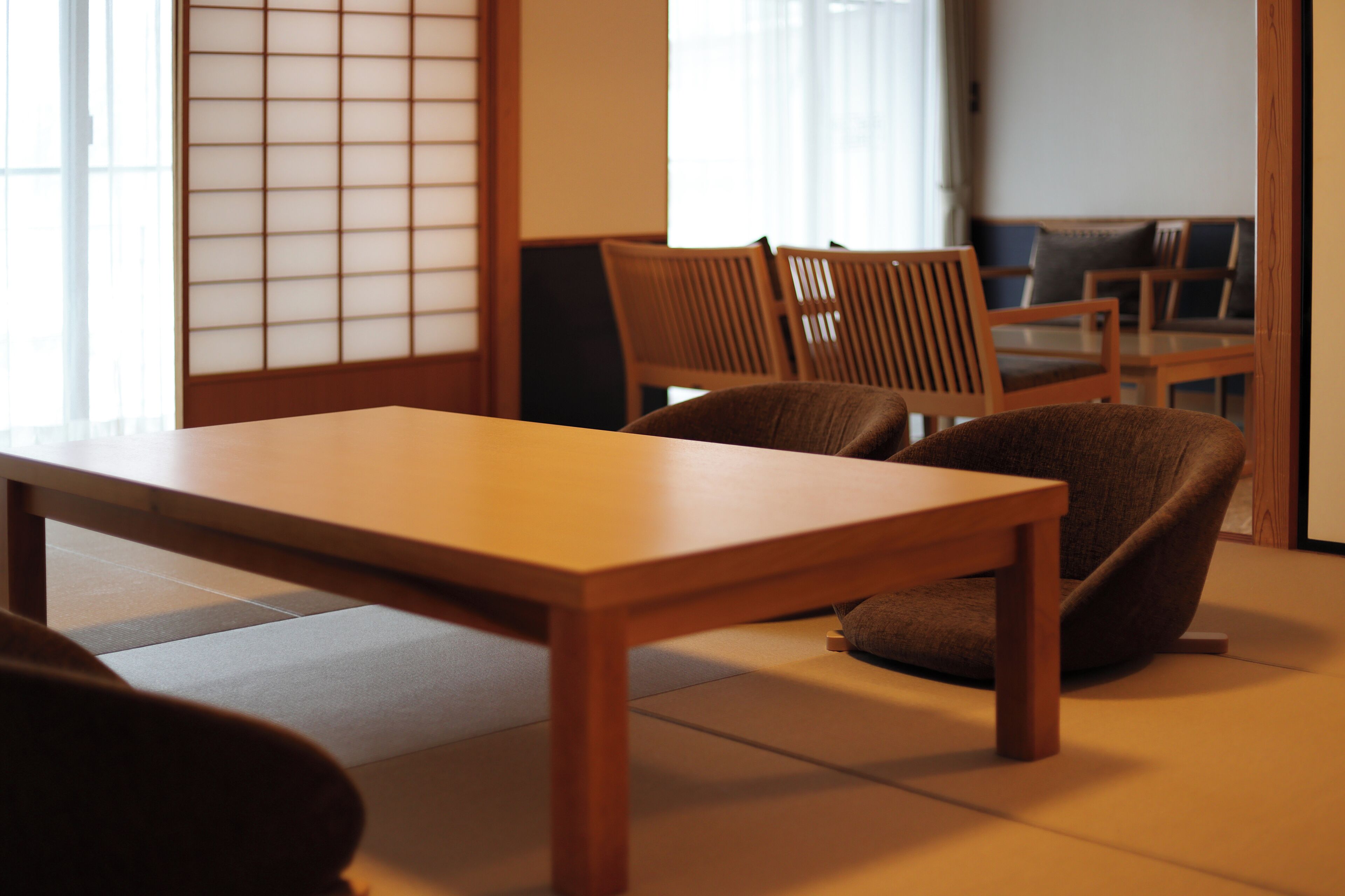 Una habitación japonesa tradicional con suelo de tatami, una mesa de madera baja y dos sillas de madera.