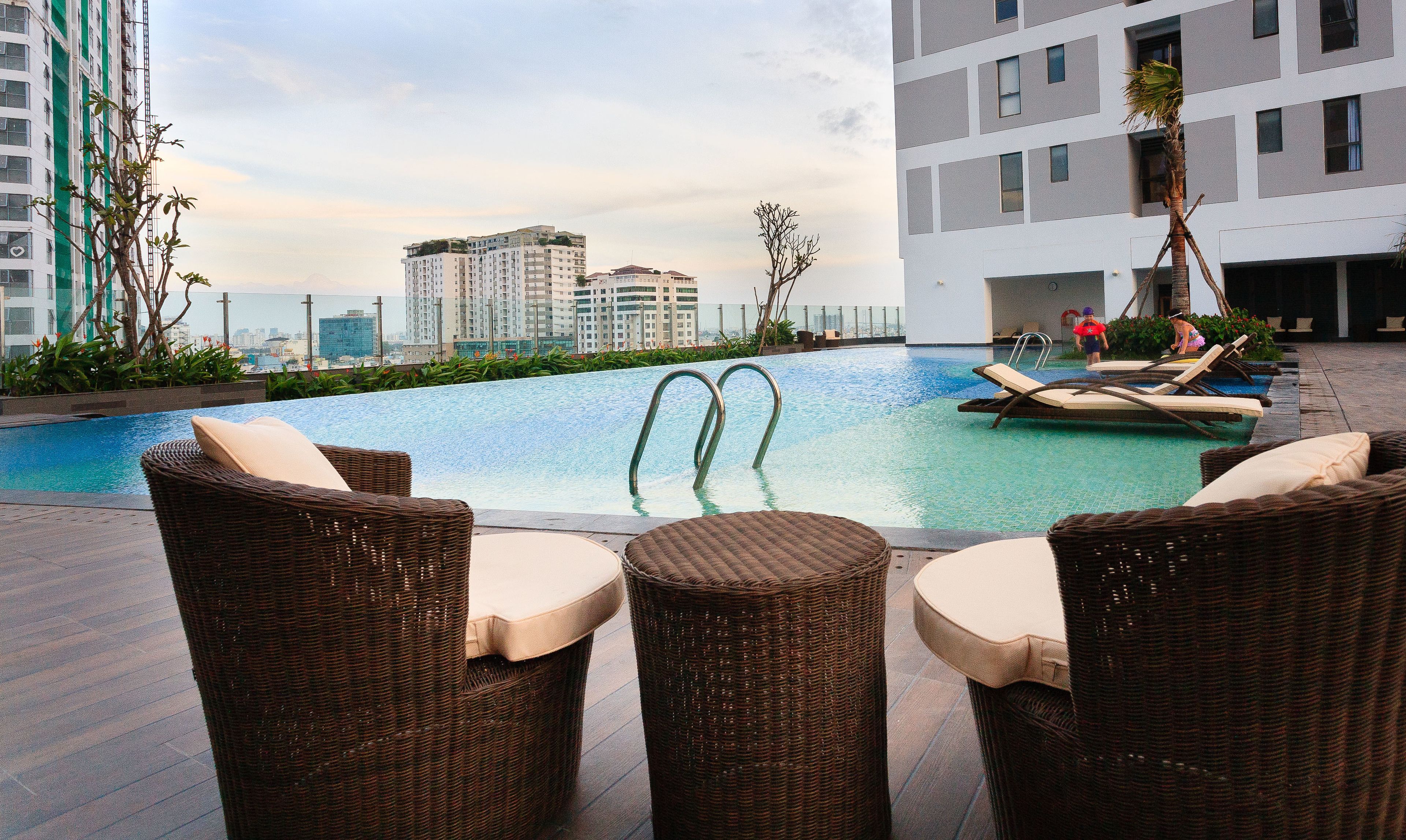 A rooftop pool with lounge chairs and a view of high-rise buildings.