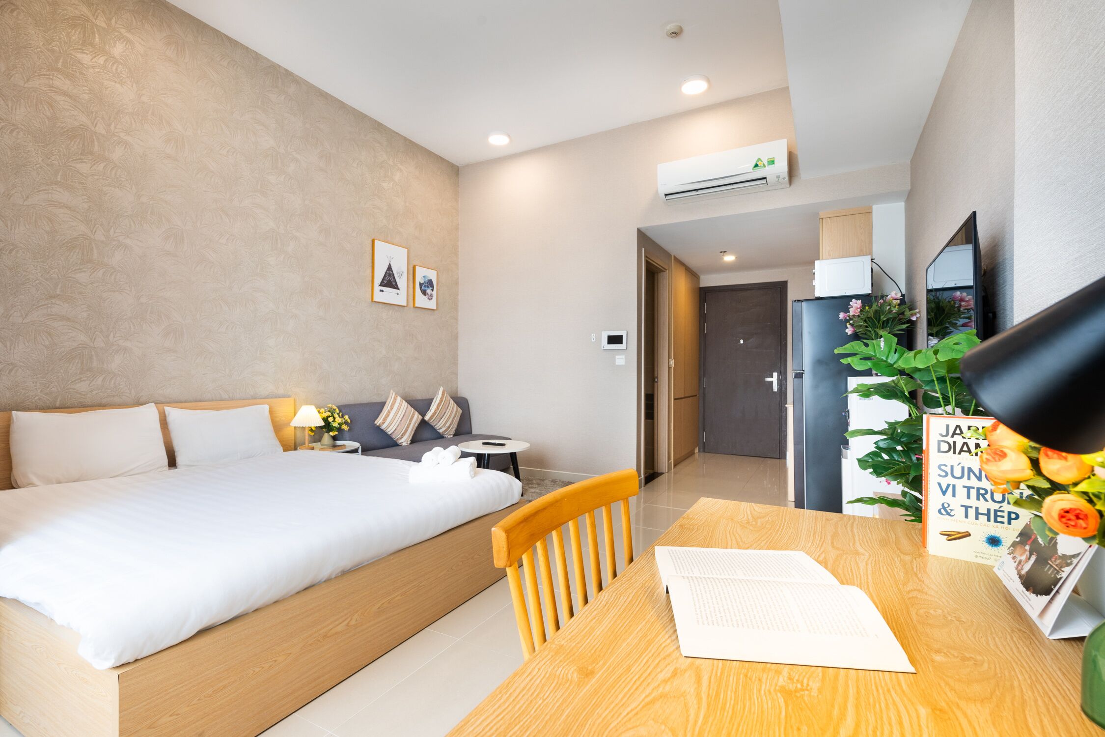 Moderni hotellihuone, jossa on suuri sänky, puinen työpöytä ja pieni pöytä.