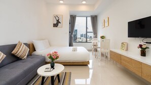 Habitación de hotel moderna con cama, sofá, televisión y vistas a la ciudad.
