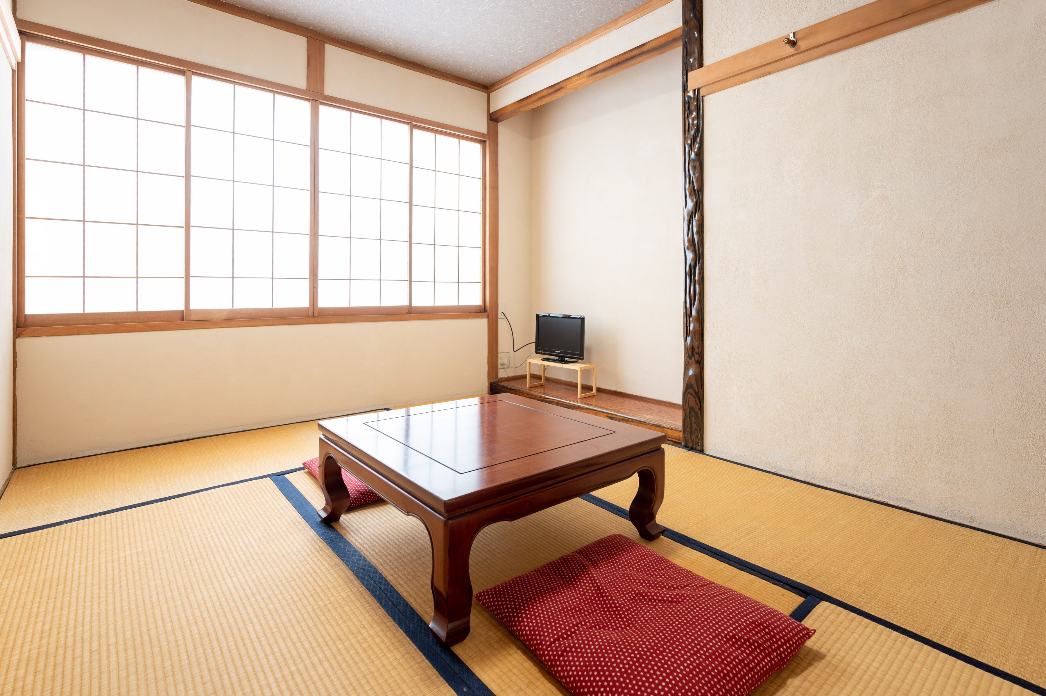 A tatami mat room with a low wooden table and a television on a small stand.
