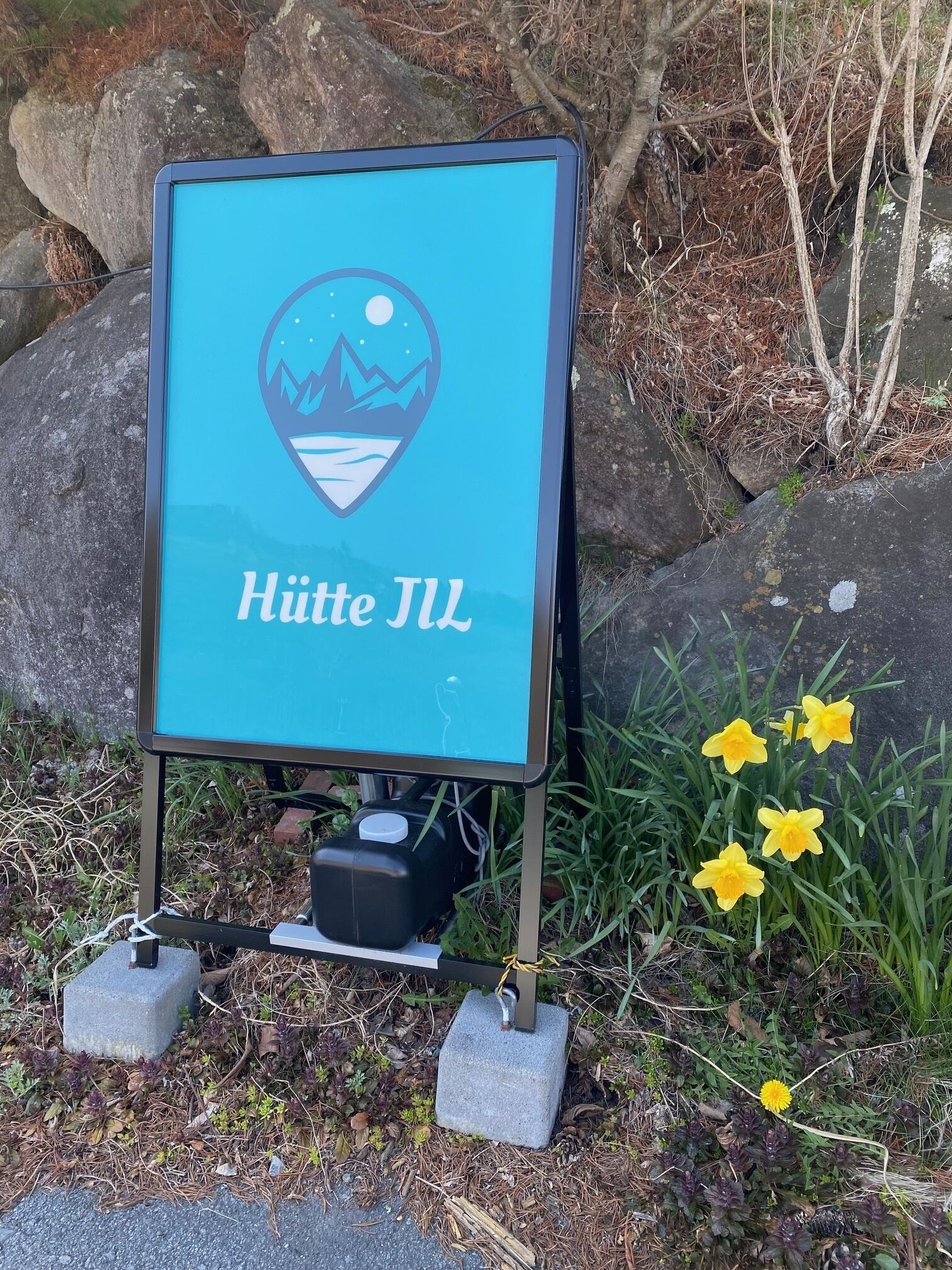 A sign with a mountain and lake graphic and the text "Hütte JIL".