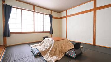 Una habitación de tatami con una mesa baja, cojines y un biombos shoji.