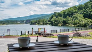 A lakeside view with a wooden bench, two cups, and a signboard. - Mountain Lodge at 1,400m Hütte Jil Shirakabako (Chino)