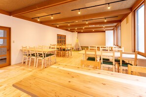 Una habitación amplia con muebles de madera, ventanas grandes y un techo alto con vigas a la vista.