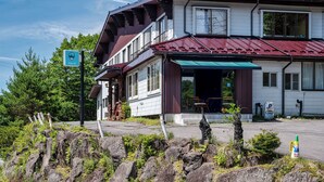 A two-story building with a red roof, a green awning, and a sign indicating a hotel. - Mountain Lodge at 1,400m Hütte Jil Shirakabako (Chino)