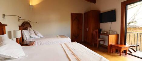 A hotel room with two beds, a desk, a chair, and a TV mounted on the wall.