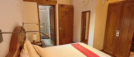 Habitación de hotel con estructura de cama de madera, un espejo grande y techo de madera con vigas a la vista.