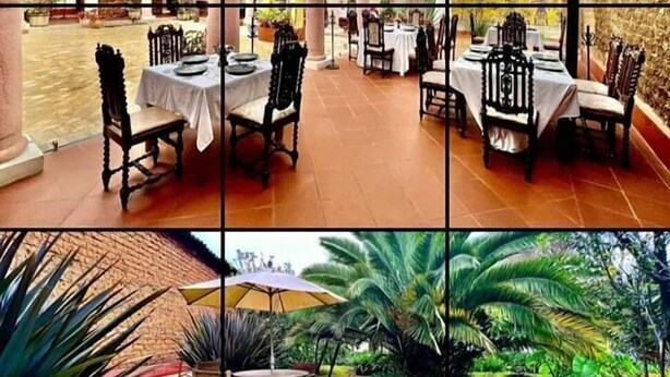 A dining area with multiple tables and chairs, a central decorative column, and a view of the outdoor garden. - Hotel Casa de Familia de San Cristobal (San Cristóbal de las Casas)