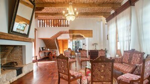 A spacious living area with a wooden floor, patterned chairs, a fireplace, and a chandelier. - Hotel Casa de Familia de San Cristobal (San Cristóbal de las Casas)