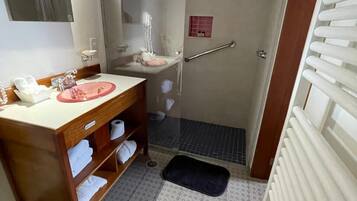 A bathroom with a wooden vanity, a sink, a mirror, a shower, and a toilet.